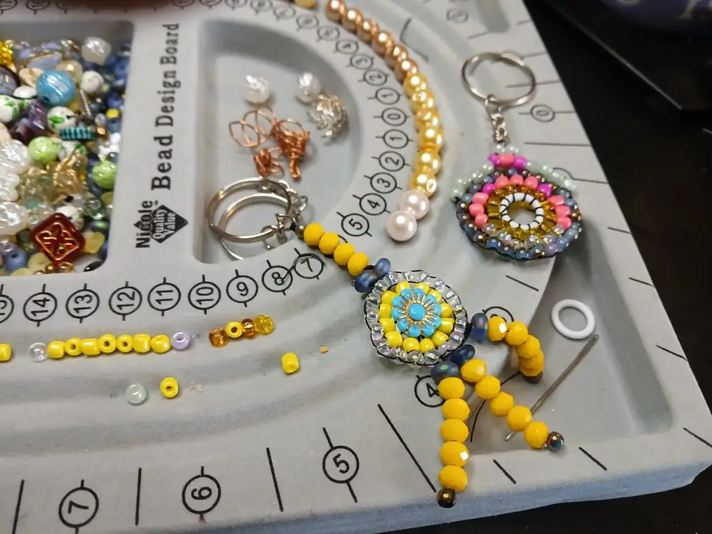 A beading station, with some finished beaded keychains, and several different beads. Showcasing some of my work in progress is part of my branding as well. It leans into authenticity.