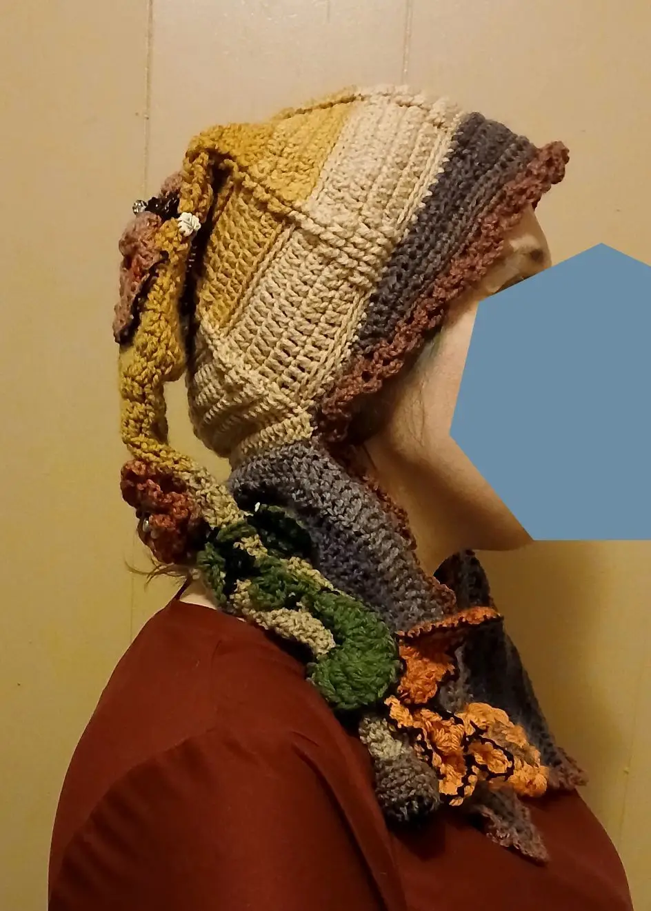 Handmade crochet elf hat with scarf in earthy tones worn in side profile, featuring textured stitches and decorative details